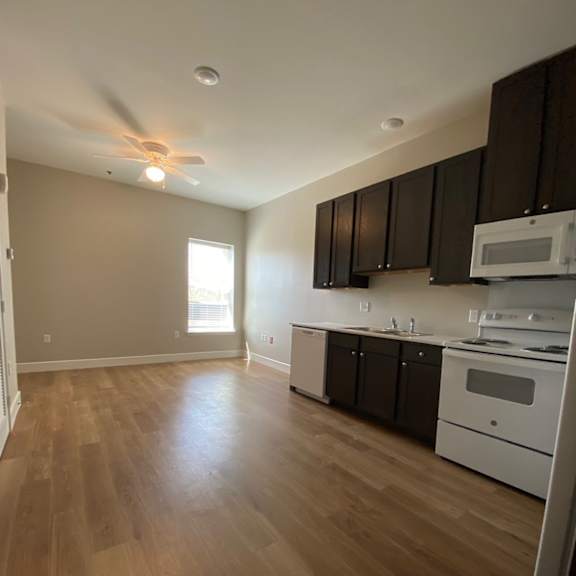 an empty kitchen with wooden floors and a ceiling fan