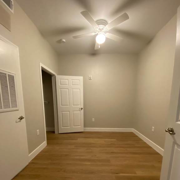a bedroom with a wood floor and a ceiling fan