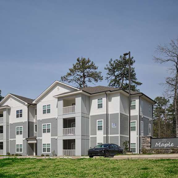 a large apartment complex named maple is shown with a car parked in front.