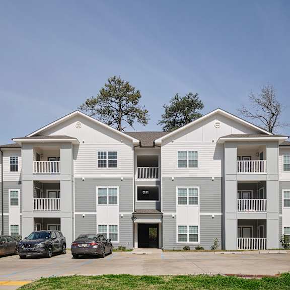 a two-story apartment building with cars parked in front.