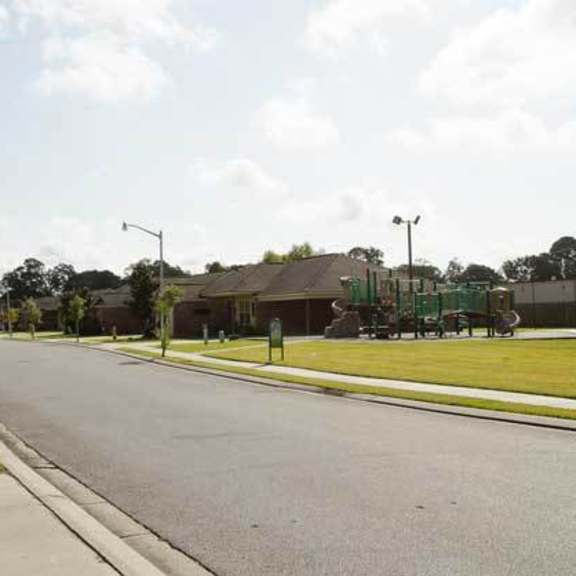 a street with houses on one side and a park on the other.