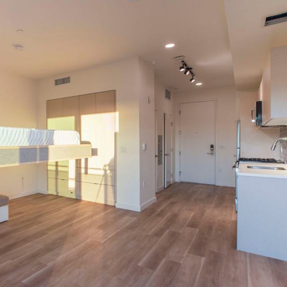 a modern bedroom with a large bed and a kitchen area.