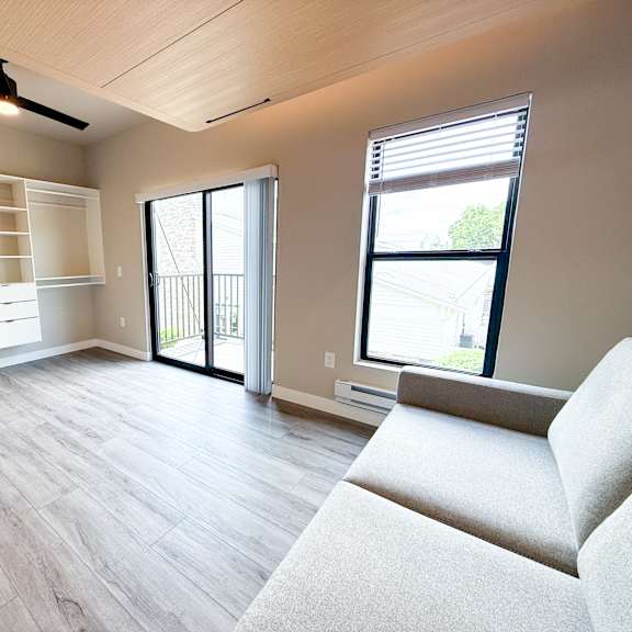 a living room with a couch, sliding glass doors, and a ceiling fan.