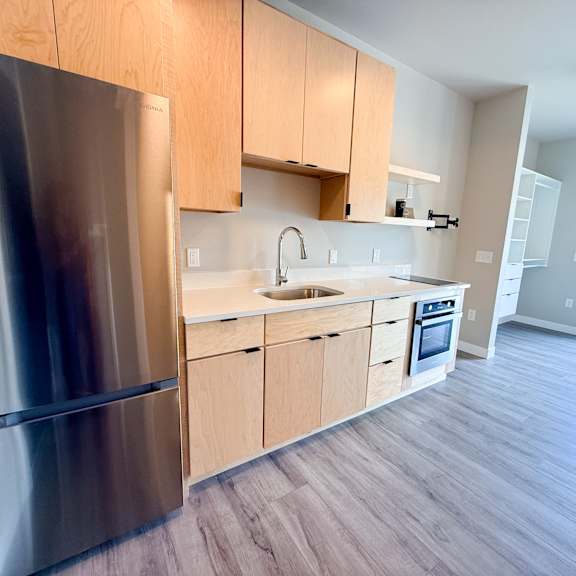 a modern kitchen with wooden cabinets and a stainless steel refrigerator.