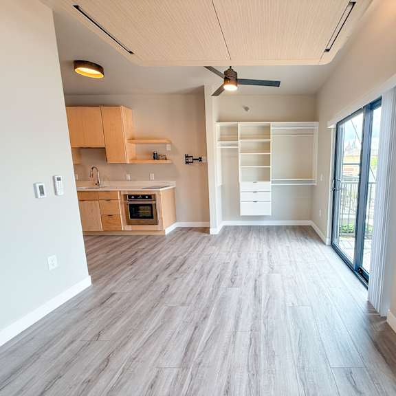 a spacious kitchen with wooden flooring and a ceiling fan.