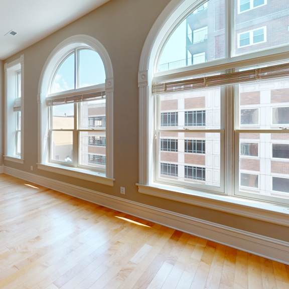 an empty living room with large windows and wood floors