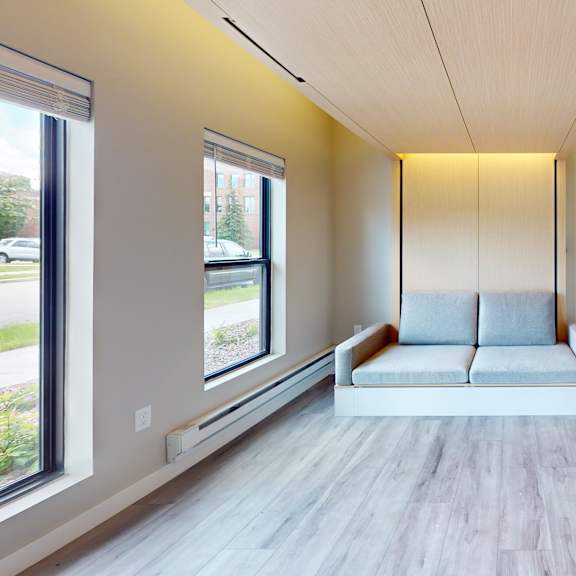 a modern living room with a grey sofa and a white cabinet.
