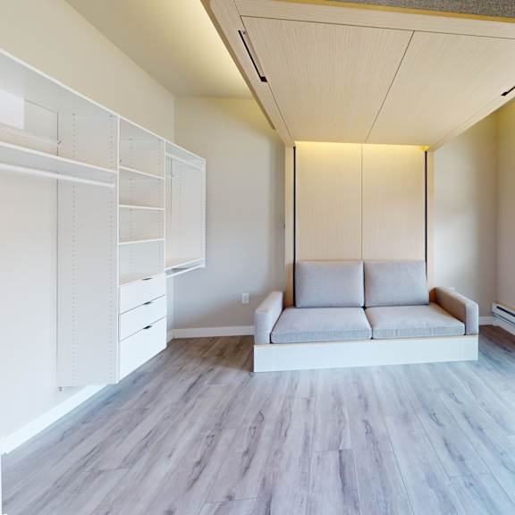 a spacious room with a white couch and a window overlooking a parking lot.