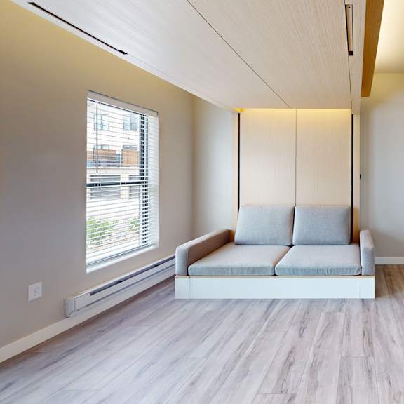 a living room with a grey couch and wooden floors.