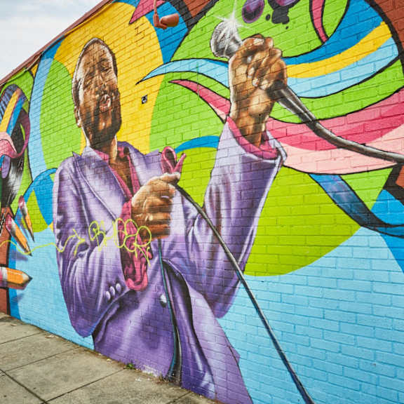 a mural of a man singing into a microphone is painted on a wall.