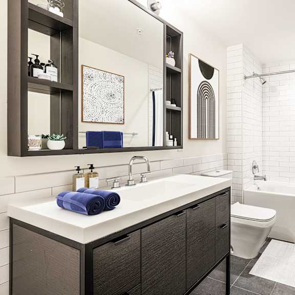 a bathroom with white tile walls and a white sink with a blue towel on it