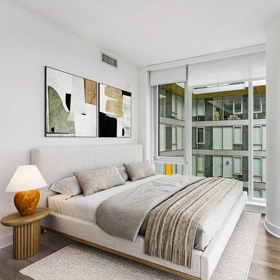 Thumbnail 3 of 6 A bedroom with a large bed and a lamp on a side table.