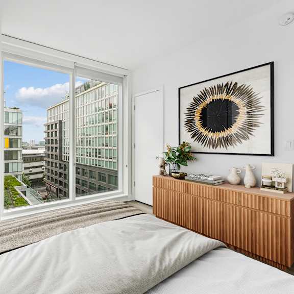 Thumbnail 2 of 6 A bedroom with a large window overlooking a cityscape.