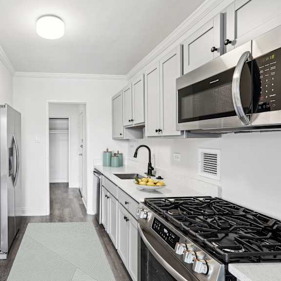 Thumbnail 3 of 13 a white kitchen with stainless steel appliances and white cabinets