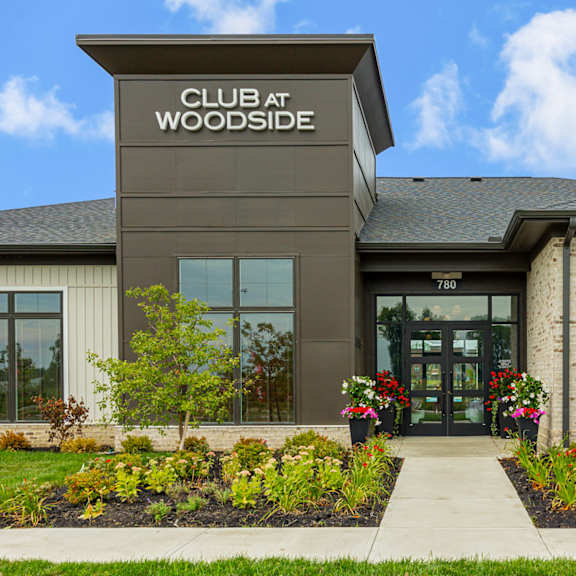 the front of a club at woodside building with a sidewalk and plants