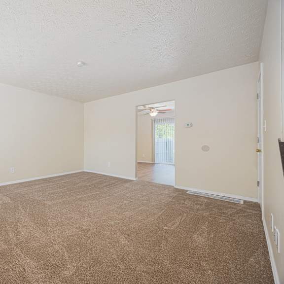 a room with a carpeted floor and a window with blinds.