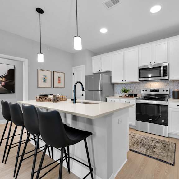 a kitchen with white cabinets and a large island with chairs.