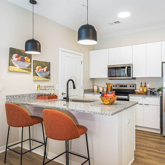 a kitchen with stainless steel appliances and a counter with two stools