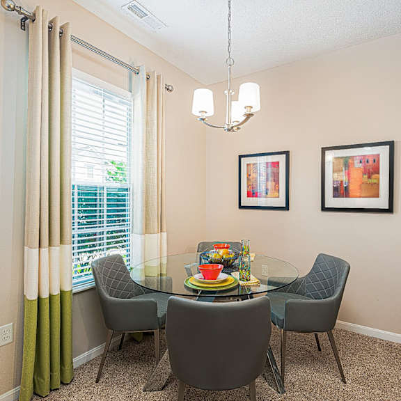 a dining room with a glass table and chairs and a window