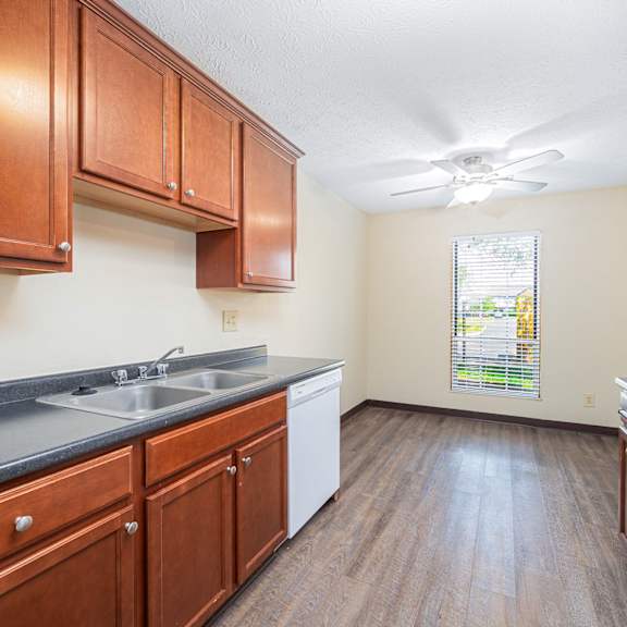 a kitchen with wooden cabinets and white appliances and a window