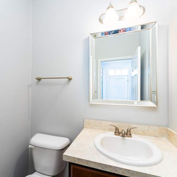 a bathroom with a toilet, sink and mirror.