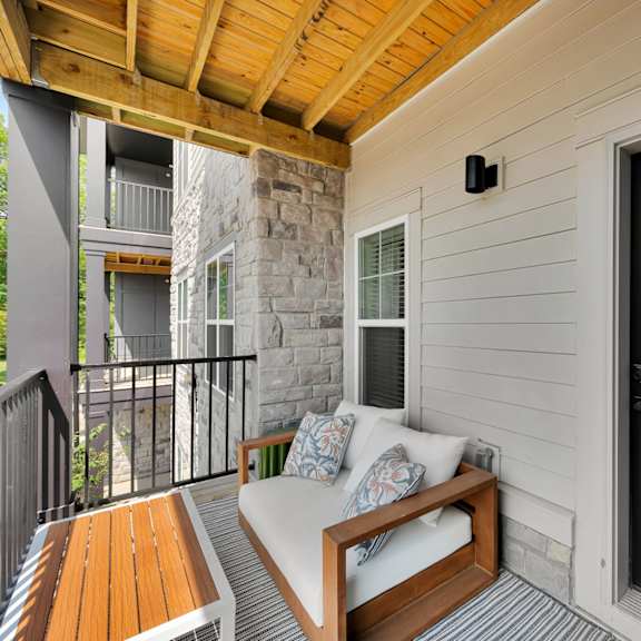 a balcony with a white couch and a wooden table.