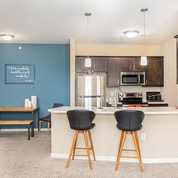 a kitchen with a bar and a living room with a table and chairs