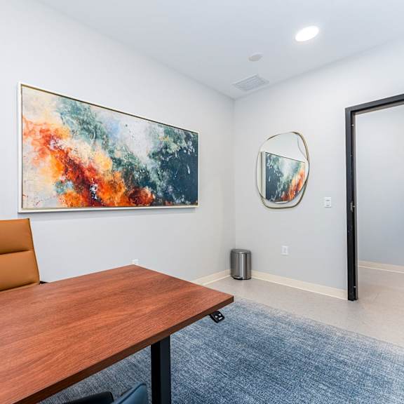 a conference room with a brown table and a painting on the wall.