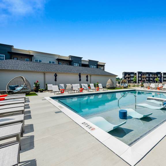a large outdoor swimming pool with lounge chairs around it.