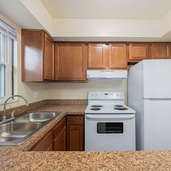 a kitchen with a stove, sink, and refrigerator.