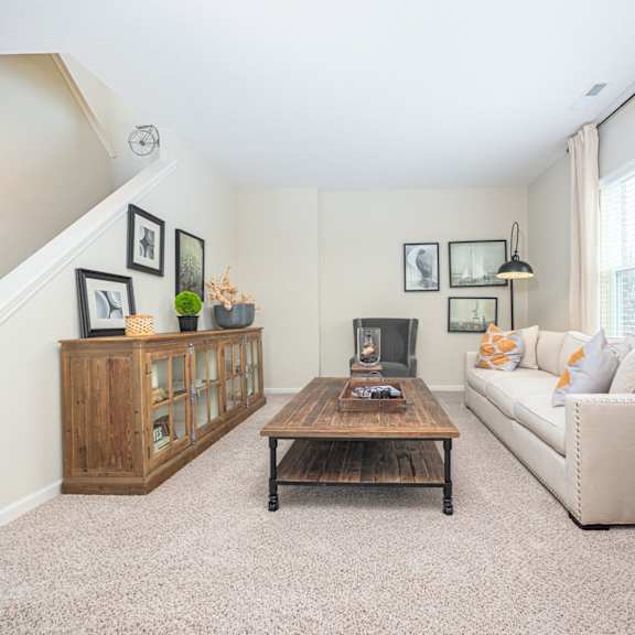 a living room with a couch, coffee table, and staircase.