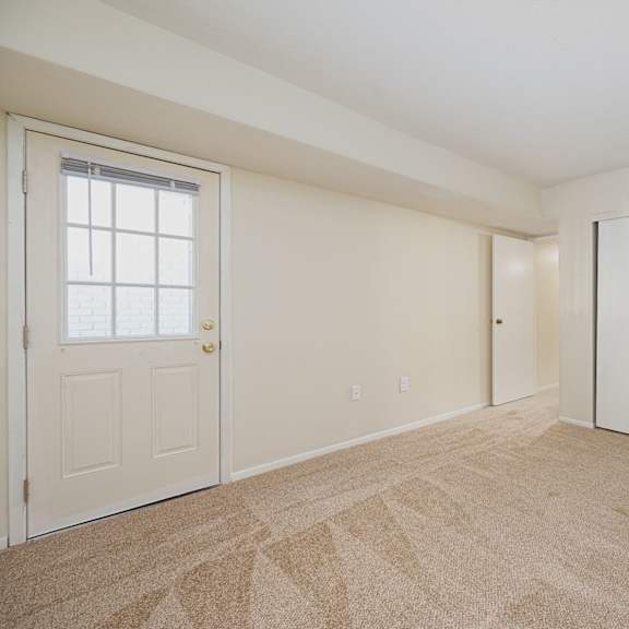 an empty living room with a door to a closet