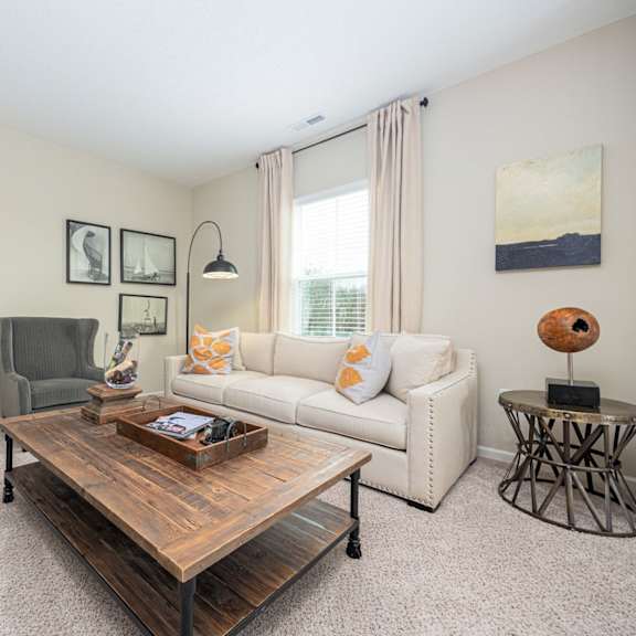 a living room with a white couch, a wooden coffee table, and a grey armchair.
