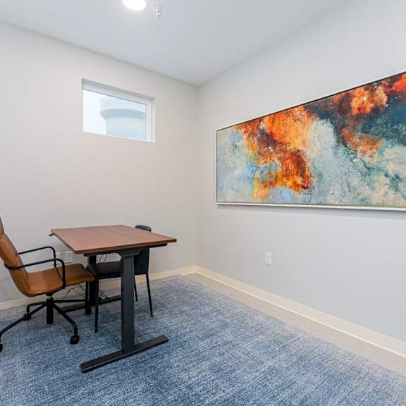 a room with a table and chairs and a painting on the wall.