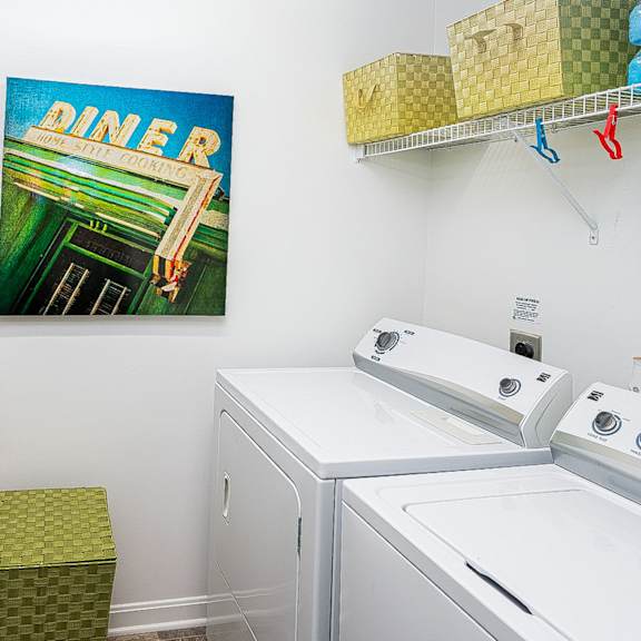 a laundry room with two washing machines and a painting on the wall