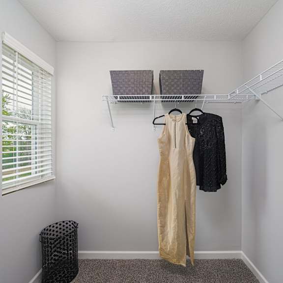 a walk in closet with a clothes rack and a window