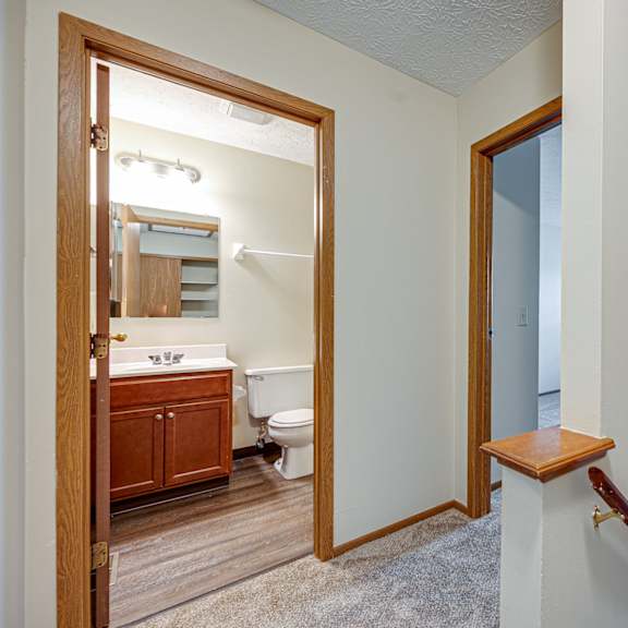 a landing leading to a bathroom with a toilet and a mirror
