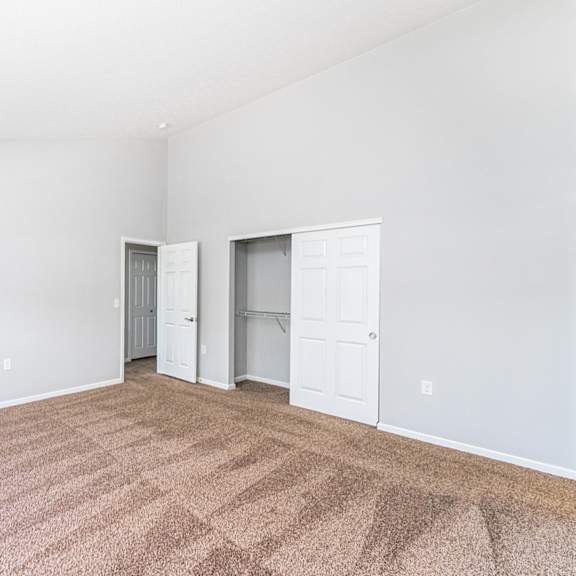 a room with carpeted floor and two white doors.