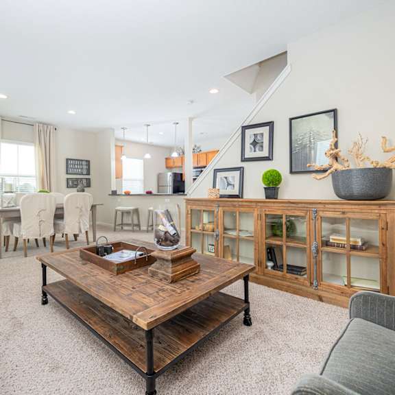 a living room with a white couch, a wooden coffee table, and a grey sofa.