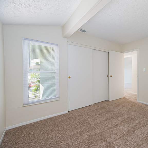 a spacious living room with carpet and a door to a bedroom