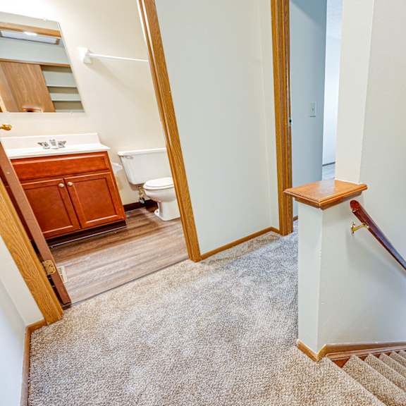 the landing of a staircase in a home with a bathroom and a toilet
