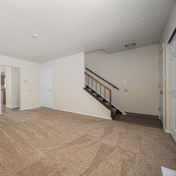a room with a carpeted floor and a staircase.