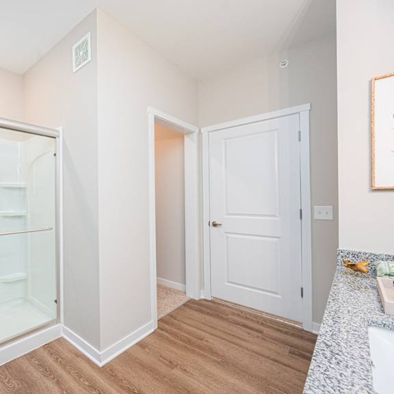 a bathroom with a glass shower and a door to a closet