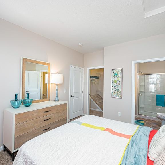 a bedroom with a bed and a mirror and a bathroom