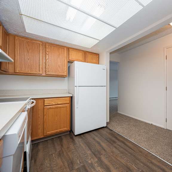 a kitchen with a white refrigerator and wooden cabinets.