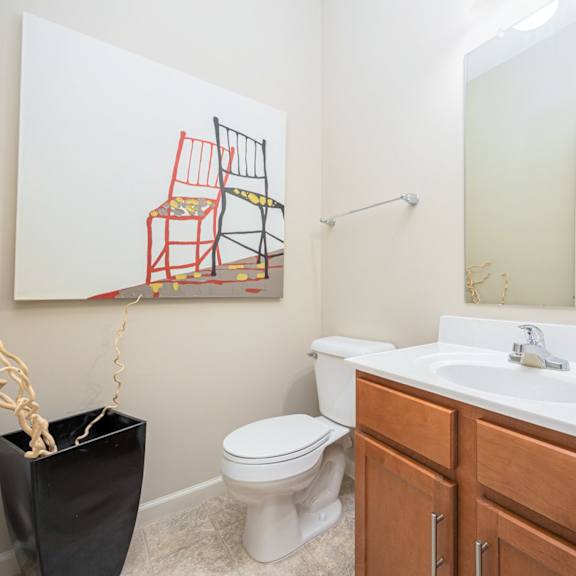a bathroom with a toilet, sink, and a painting of a chair.