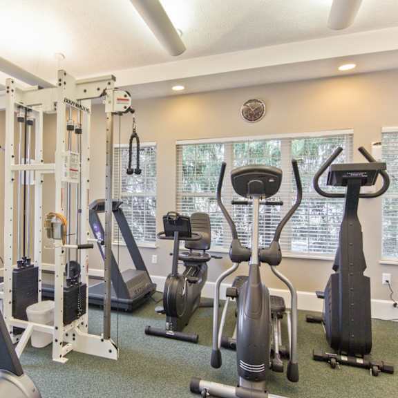 a gym with cardio machines and weights at the enclave apartments