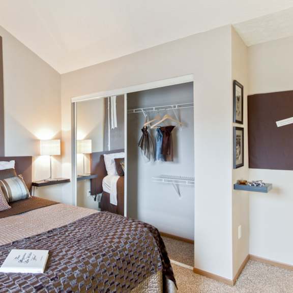 a bedroom with a bed and a closet with clothes hanging on the wall