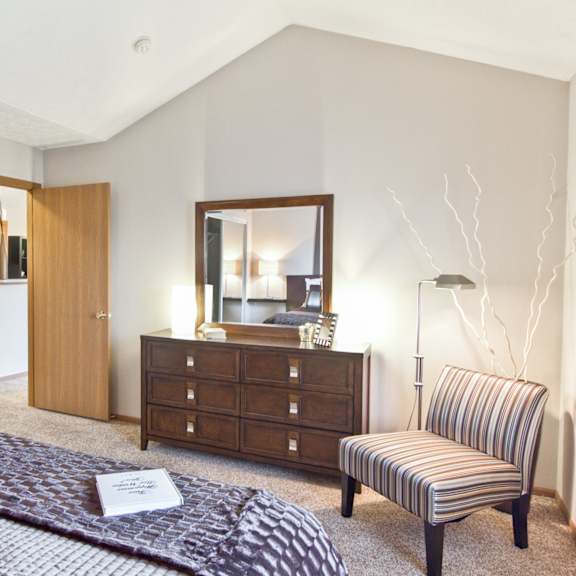 a bedroom with a bed and a chair and a dresser
