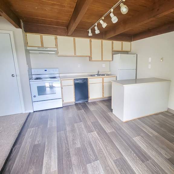 a kitchen with white cabinets and a wooden ceiling